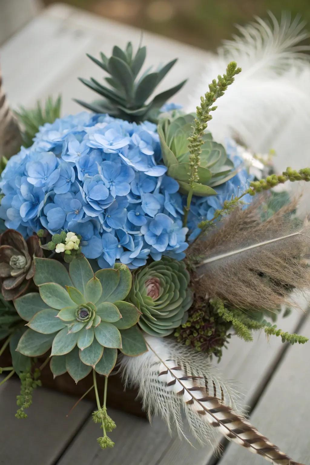 An eclectic centerpiece displaying azure hydrangeas, succulents, plus feathers.