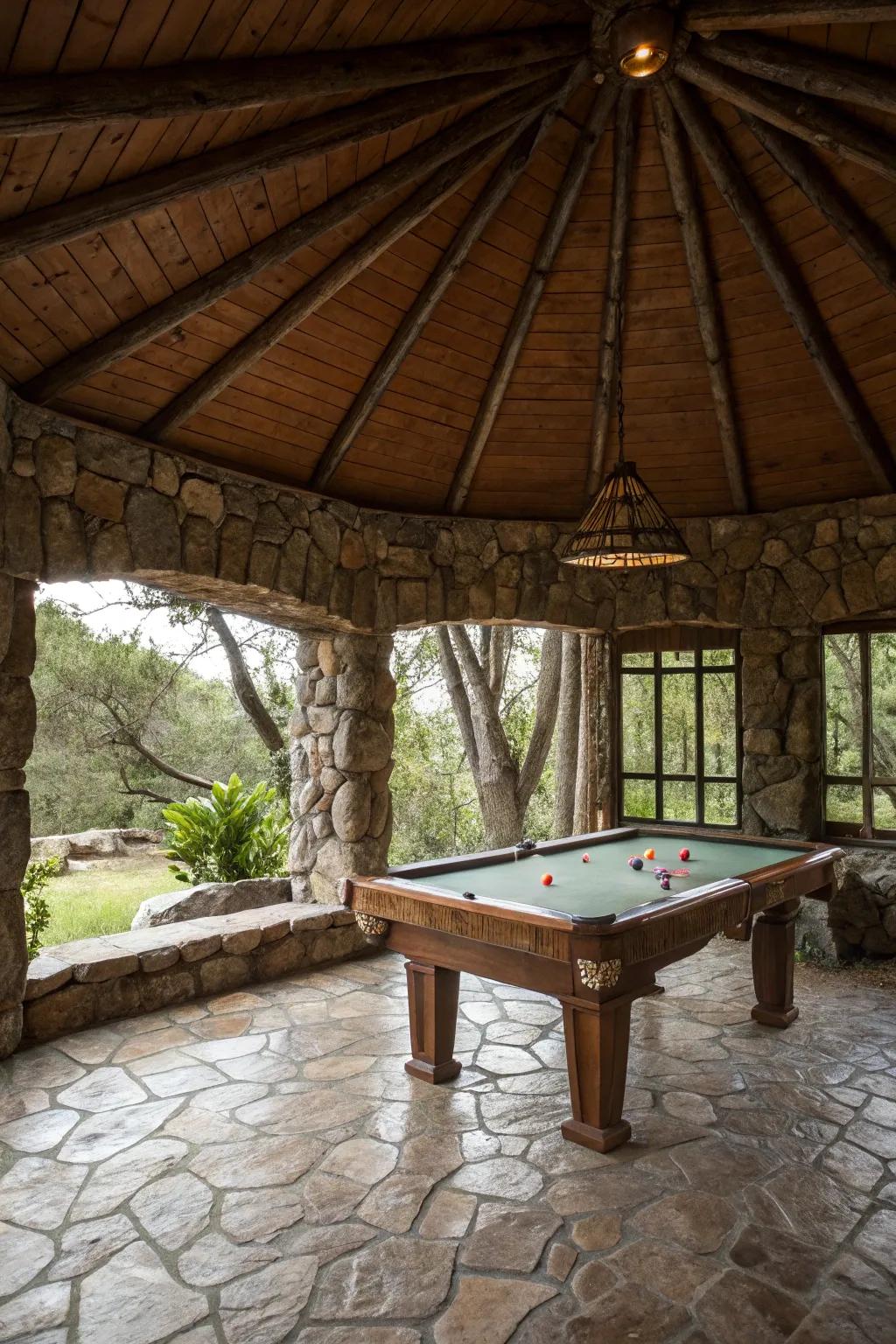 A rustic stone gazebo housing a billiards table in a natural setting.